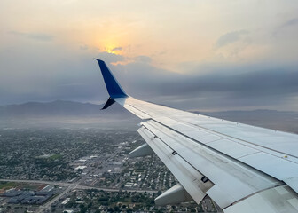 Airplane wing against sunset, while flying over Salt lake city, utah