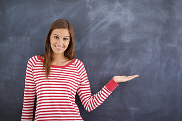 May I direct your attention right here. Portrait of a gorgeous young woman standing in front of a blackboard.