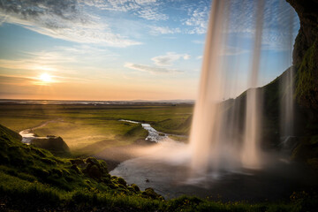 Magical view of a sunset over a vast field with a waterfall