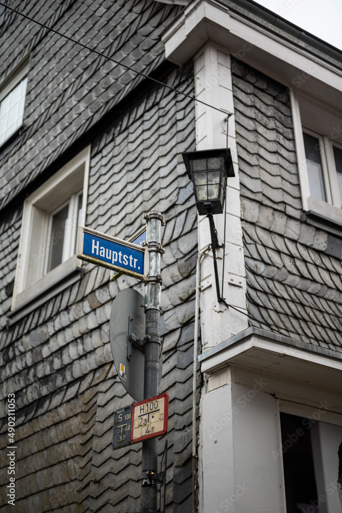 Poster Vertical shot of a house on a road with road signs on a pole near it in Germany