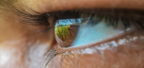 Macro shot of a brown female eye reflecting the nature © Rafiul Munna/Wirestock