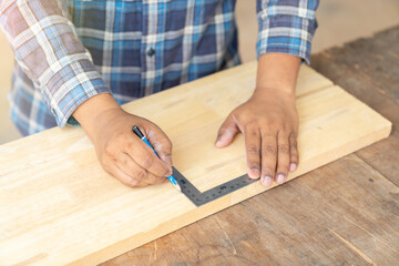 The carpenter use solid square to measure wood sheet.