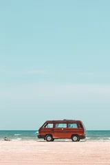 Foto op Plexiglas Lichtblauw Verticale opname van een rode reisbus op een strand