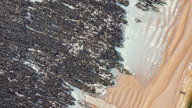 Aerial view of the stones and chalk flats at Peacehaven Beach.