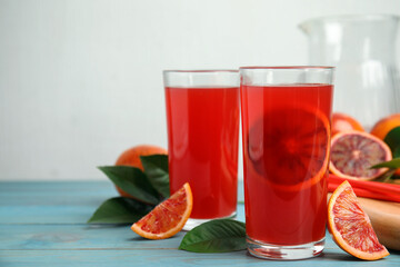 Tasty sicilian orange juice and fruits on light blue wooden table, space for text