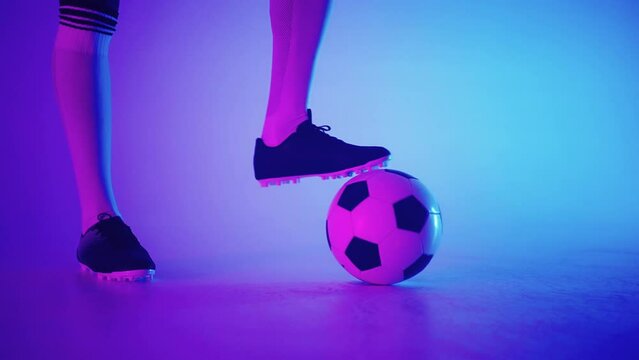 professional footballer is dribbling ball in studio, closeup view of feet in football boots