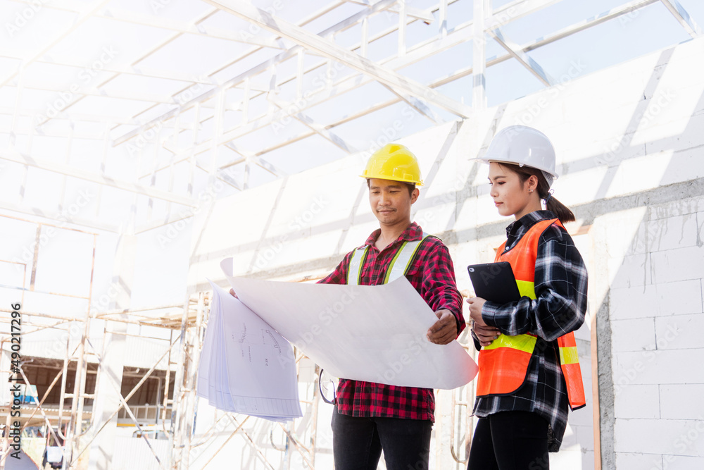 Poster architect and client discussing the plan with blueprint of the building at construction site. asian 
