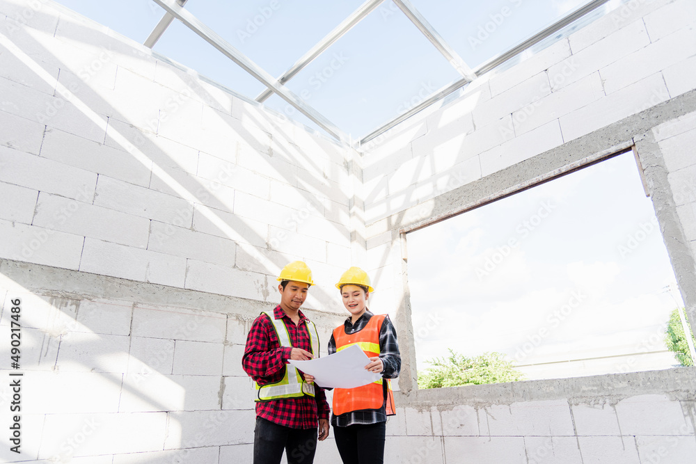 Poster architect and client discussing the plan with blueprint of the building at construction site. asian 