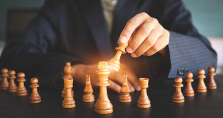 Confident businessman moving chess figure in competition success play. Management, strategy, or leadership concept.