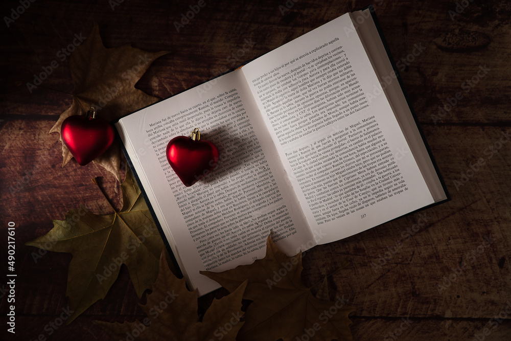 Wall mural Open book with heart-shaped Valentine's Day decorations and leaves