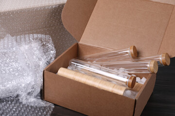 Test tubes in cardboard box and bubble wrap on dark wooden table