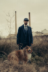 Vertical shot of a Hispanic male in retro 1900s gangster fashion posing with his dog