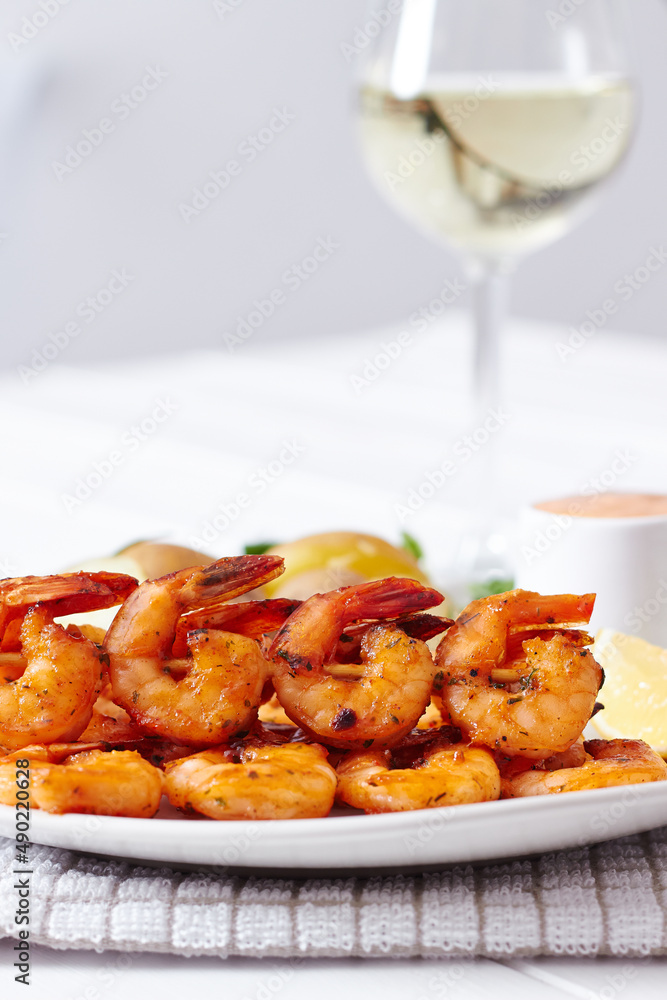 Poster closeup of a roasted peel prawn in white plate served with a white wine