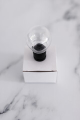 Think outside the box concept with idea lightbulb on top of white box on white marble