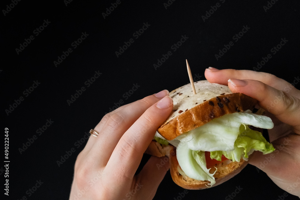 Sticker a hand holding a sandwich in the hand and isolated in a black background