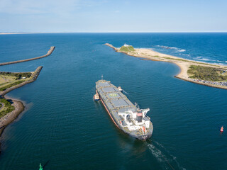 Aerial view of a cargo ship being tagged with small boats near a harbor
