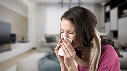 Unhappy sad young female suffering from fever and flu, blowing nose in napkin