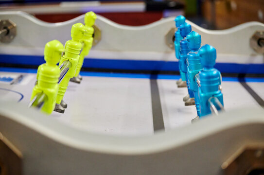 Soft Focus Of Color Coordinated Men Figures On Rods Of A Foosball Table