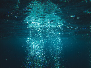 Underwater shot of sun rays going through deep ocean making water bubbles - obrazy, fototapety, plakaty