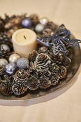 Vertical of a plate full of acorns painted in silver and Christmas tree decorations around a candle