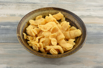 Cheese corn snack tubes in ceramic brown snack bowl on table