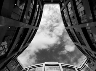 Grayscale low angle shot of modern buildings against the sky.