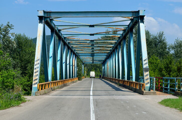 Truck driving on a truss bridge with asphalt road on a sunny day