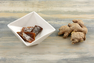 Ginger candy chews pieces in white candy dish with fresh ginger root