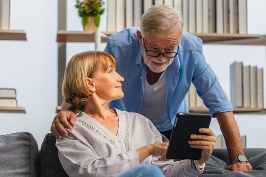 Mature woman and senior man using smartphone talking on video call on cozy sofa at home, Portrait of Cheerful senior couple in living room, Happy family concepts