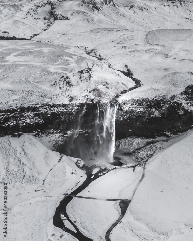 Wall mural aerial view of a snowy land with a frozen waterfall