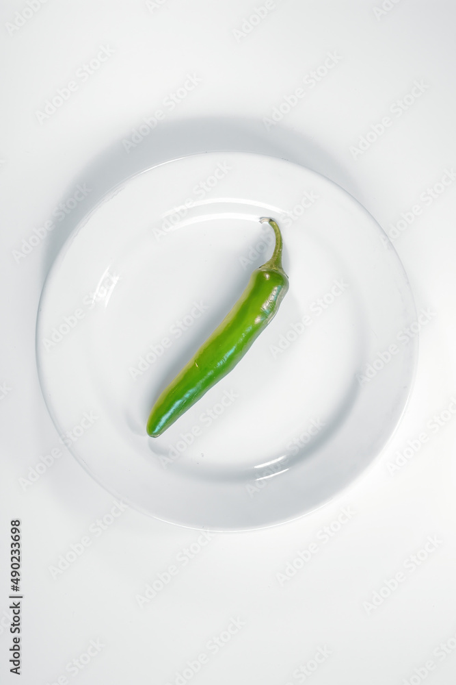 Canvas Prints Vertical shot of a green pepper on the white plate