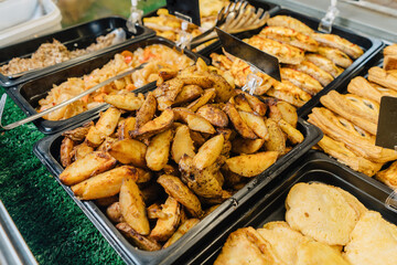 Potato wedges, on a baking sheet in the display case. Showcase of a real food store.