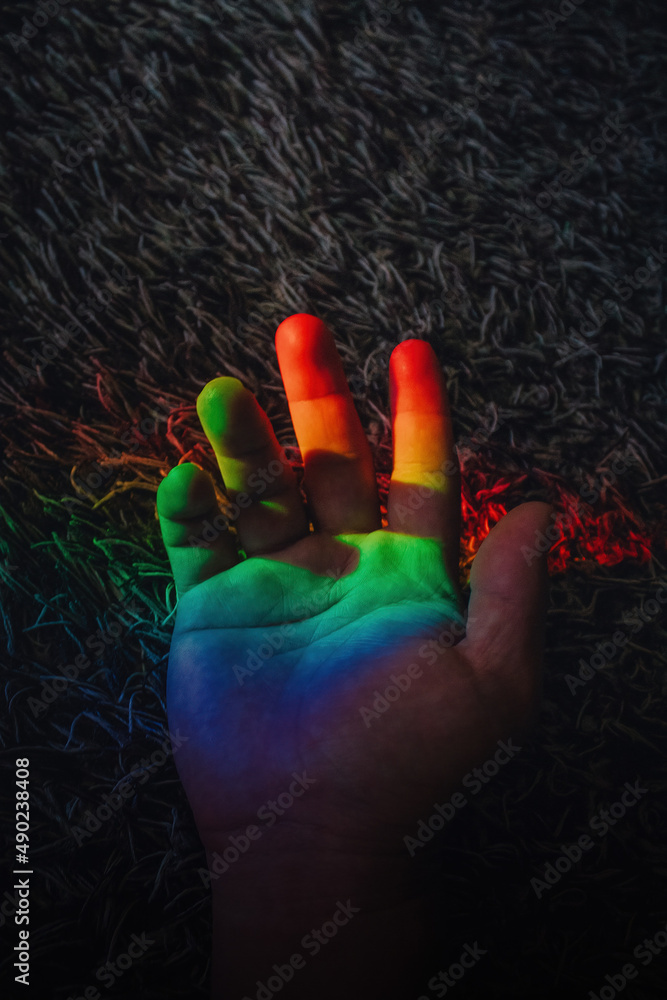 Wall mural Vertical closeup shot of the rainbow on the male hand with the furry carpet on the background