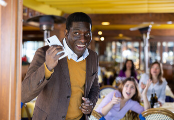 Portrait of satisfied cunning african american man stealing mobile phone of frightened upset young...