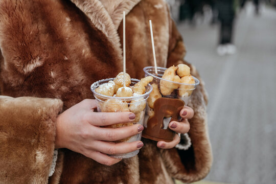 Close-up photo of woman holding two portions of festive pastry street food at christmas market