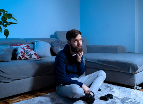 Sad Lonely Depressed Man Sitting Alone In Front Of Tv Late At Night, Game Controller In Front Of Him. Wasting Time, Depression, Being Lazy