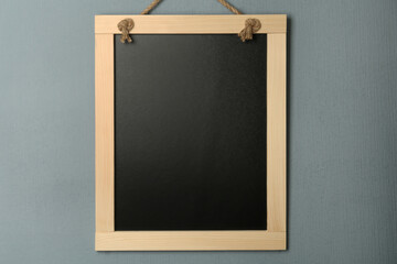 Clean small black chalkboard hanging on grey wall