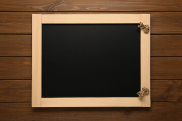 Clean small black chalkboard on wooden table, top view