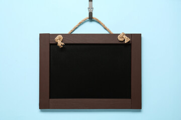 Clean small black chalkboard hanging on light blue background