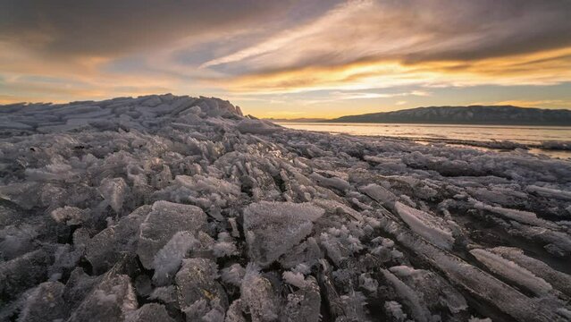 Sunset timelapse moving over broken ice on lake in Utah during winter viewing the icy texture and pattern.