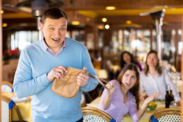 Insidious adult man trying to snatch handbag of young woman visiting restaurant for lunch..
