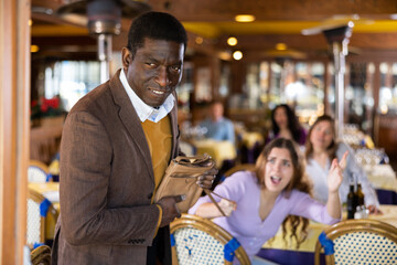 African-american man leaving restaurant after stealing handbag from woman.