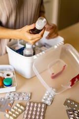 Obraz na płótnie Canvas Closeup female hand placing medicament domestic first aid kit. Storage organization emergency supply
