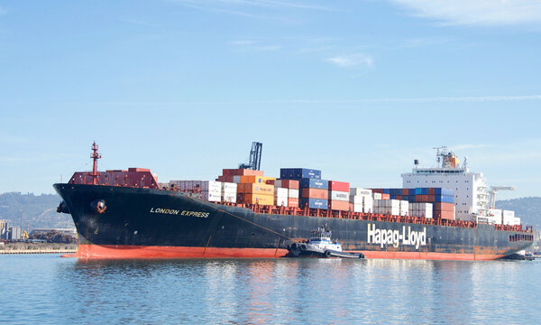 Oakland, CA - March 01, 2022: Tugboats assisting Hapag-Lloyd cargo ship LONDON EXPRESS maneuver into the Port of Oakland.