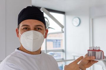 Fototapeta na wymiar Male dentist holding a dental implant model. Dental clinic concept