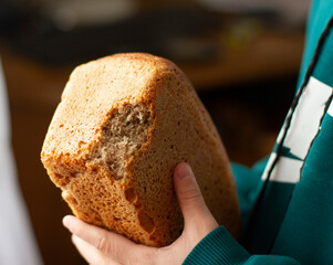  надкушенный  свежий серый  хлеб в руках