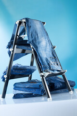 Denim jeans at chair or shelf of rack near blue background texture in shop. Front view of classic jeans fashion.