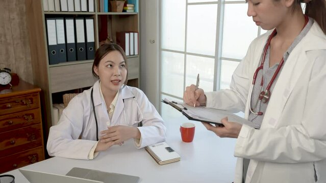 4K 50fps, Asian female medical student, studying patient information with a doctor, at the hospital, writes a note on a white paper. , health and medical concepts