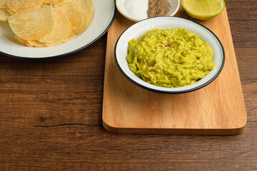 Fresh guacamole in a bowl on a wooden cutting board
