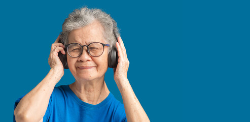 Cheerful senior woman wearing wireless headphones to listen to a favorite song with a smile